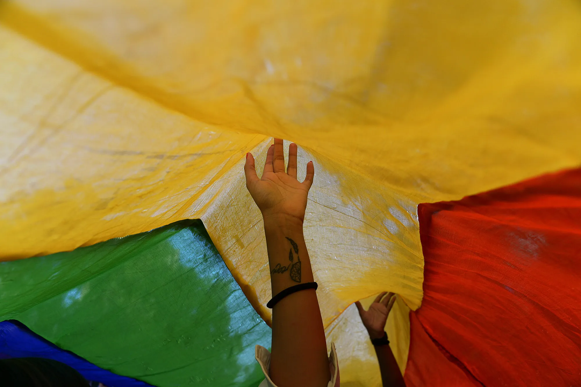 Indian members and supporters of the lesbian, gay, bisexual, transgender (LGBT) community walk underneath a rainbow flag during a Gay Pride Parade in New Delhi on November 30,2014.