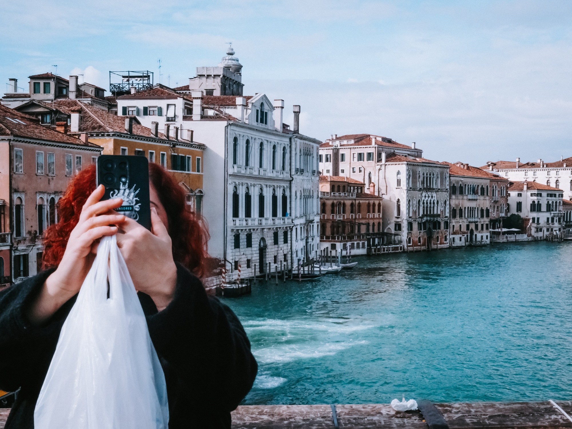 A tourist with red hair raises a smartphone to photograph the Grand Canal from Ponte dell Accademia during the Carnival period in Venice, Italy, February 8, 2026. The close range gesture illustrates dense visitor activity and constant filming in the city. (Photo by Romain Costaseca / Hans Lucas / AFP via Getty Images)