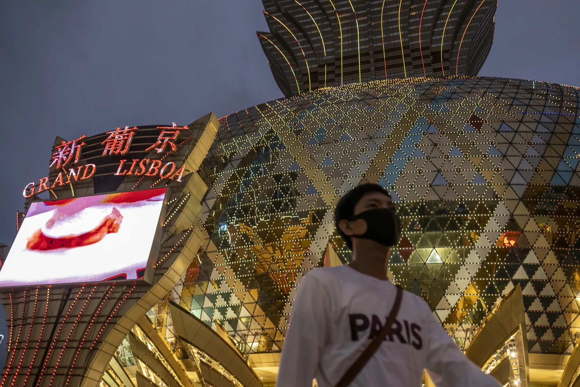 A pedestrian in a face mask passes the Casino Lisboa, operated by SJM Holdings, in Macau.