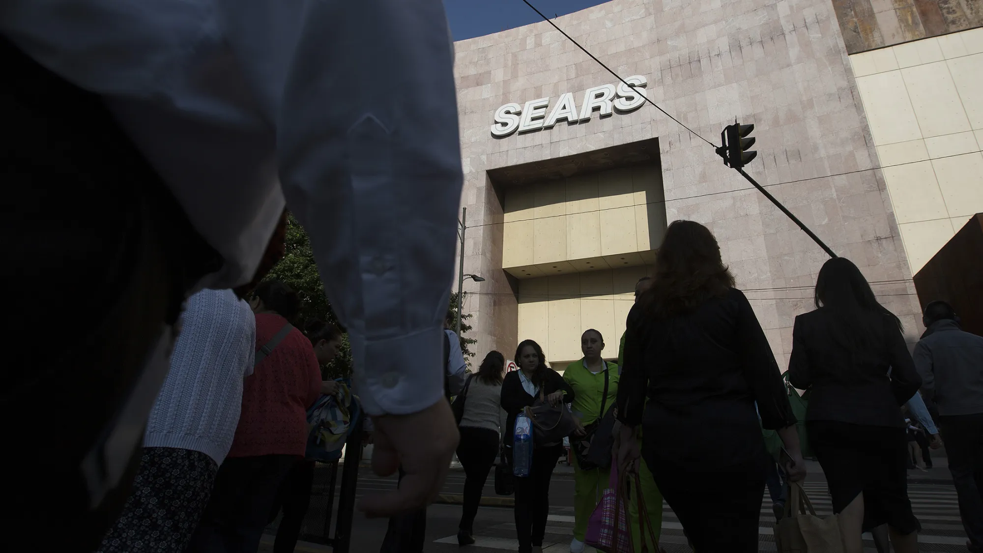 Pedestrians walk past a Sears store.
