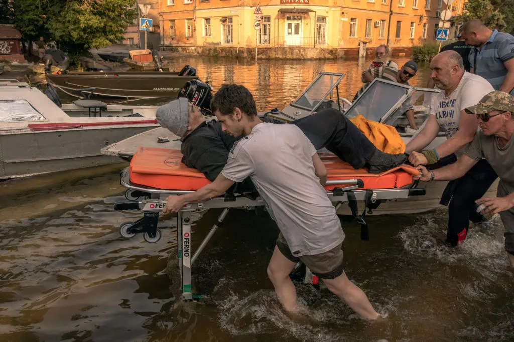 Volunteers&nbsp;push a stretcher carrying an elderly person who was evacuated from a flooded area in Kherson, June 9.