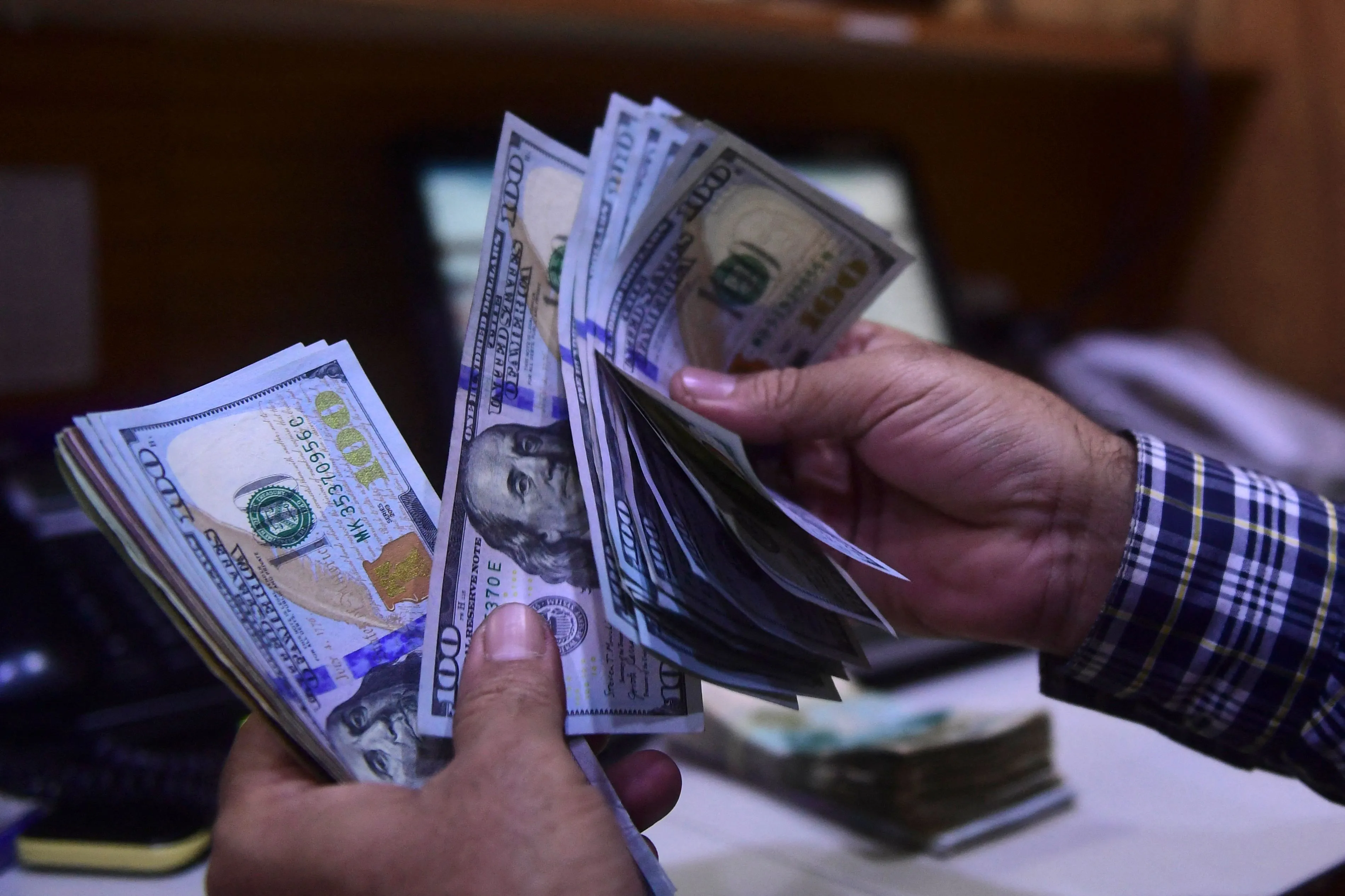A dealer counts US dollars at a money exchange market.