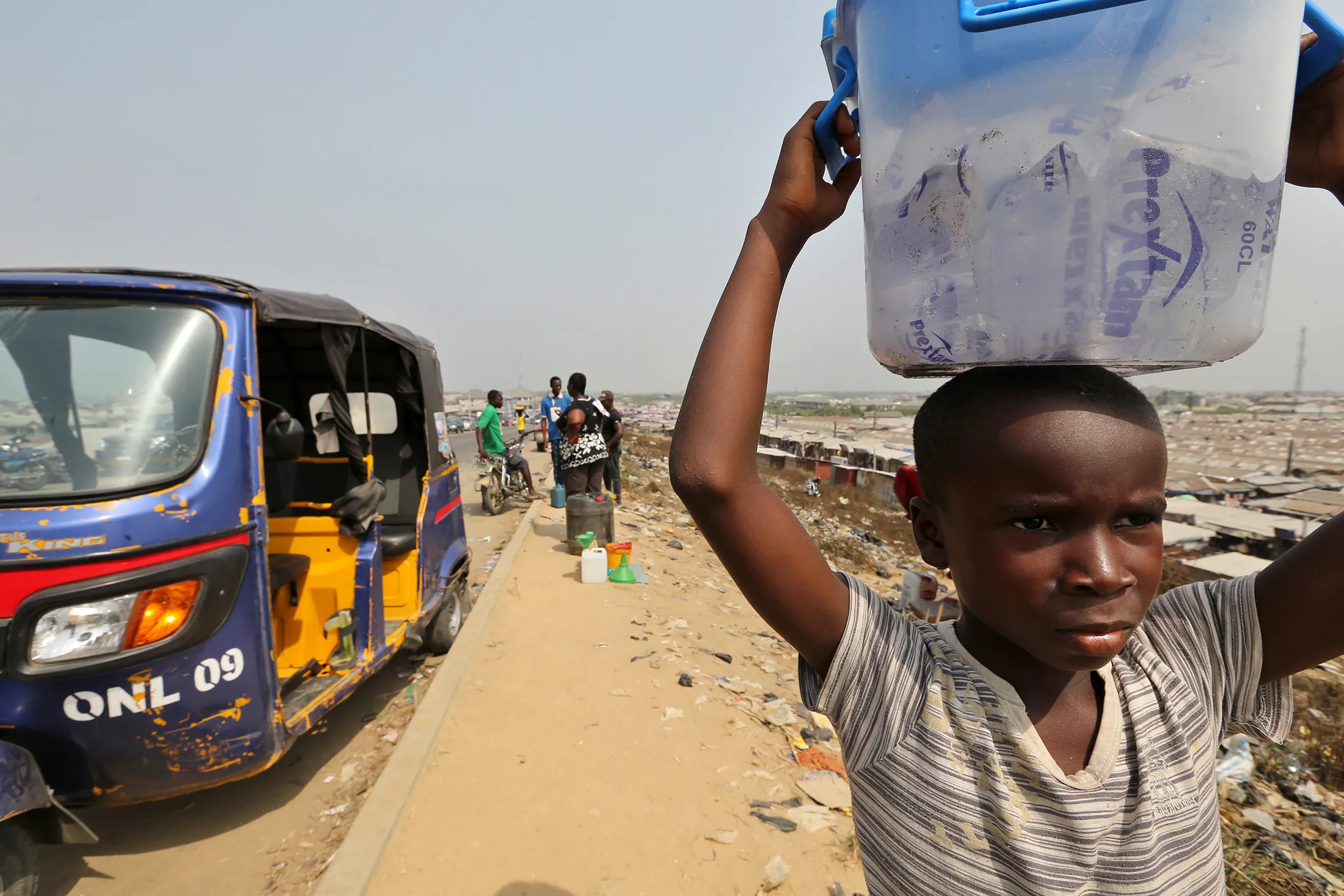 A young boy sells sachets of Prextam water from a plastic container as he stands on the roadside near the Swali market in Yenagoa, Nigeria, on Thursday, Jan. 14, 2016.
