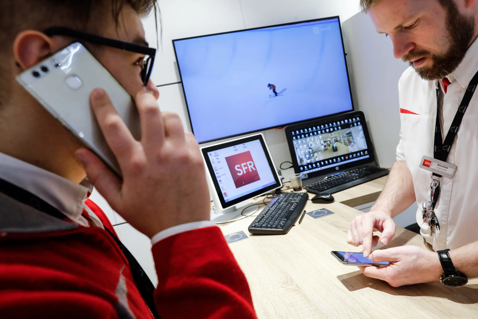 Employees use smartphones inside an SFR mobile phone store, operated by Altice NV, in Lille.