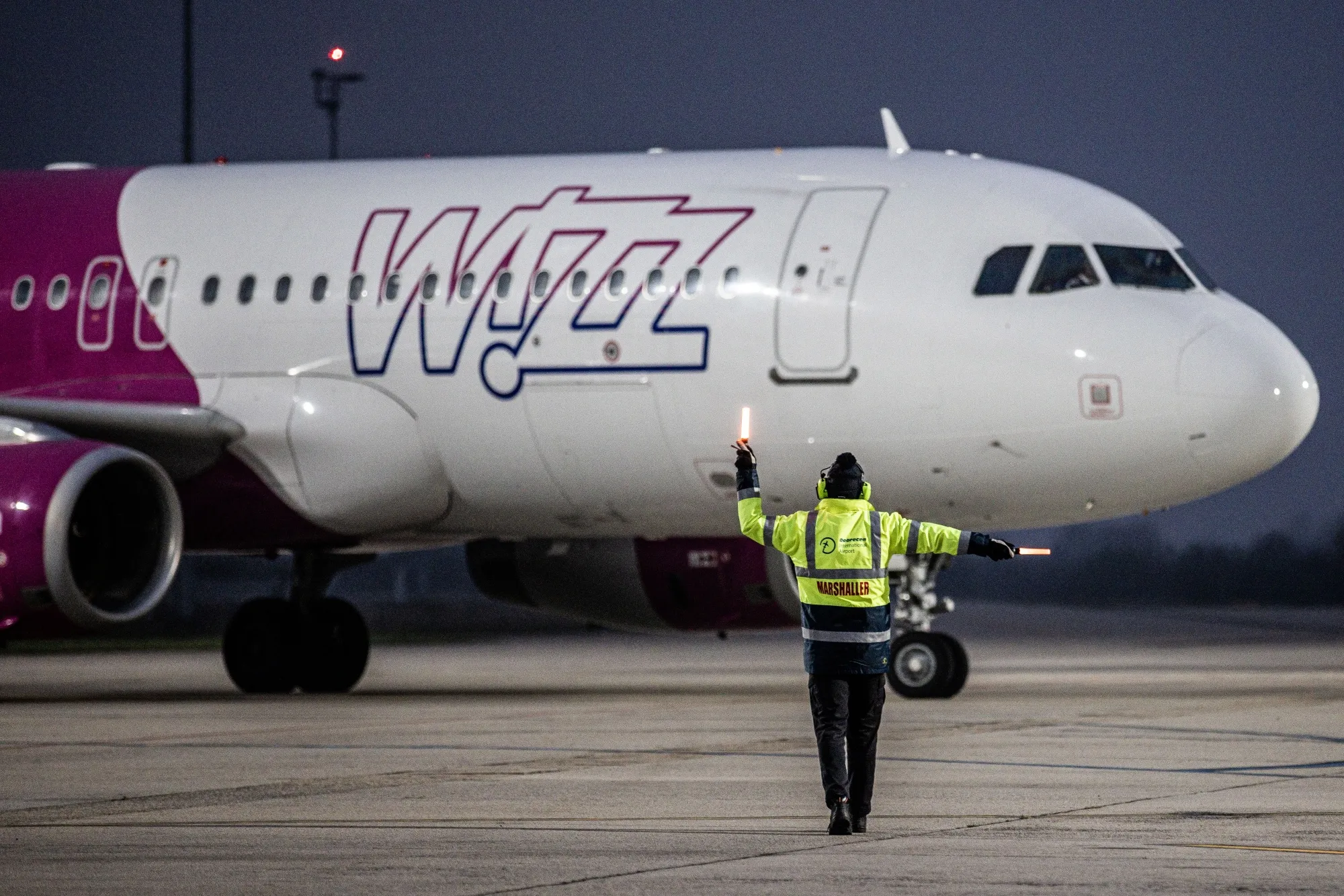 A member of ground crew directs a Wizz Air Holdings Plc passenger aircraft to the gate at Debrecen International Airport in Hungary.