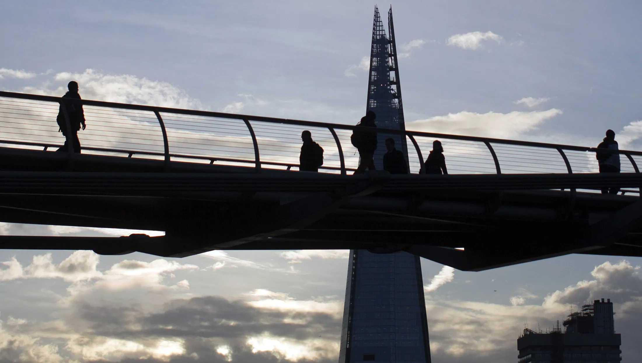 Pedestrians use the Millennium Bridge near the Shard tower in London.
