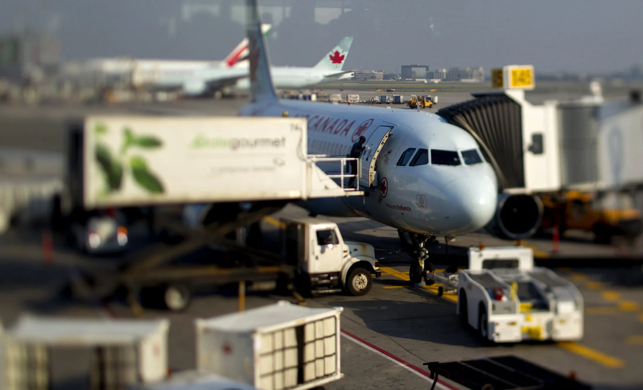 An Air Canada aircraft sits at a gate in this photo taken with a tilt-shift lens at Toronto Pearson International Airport in Toronto, Ontario, Canada, on Wednesday, July 3, 2013. Air Canada predicted further pressure on fares this year after its first-quarter yield dropped as competitors added seating and offered lower prices on some routes in North and South America.
