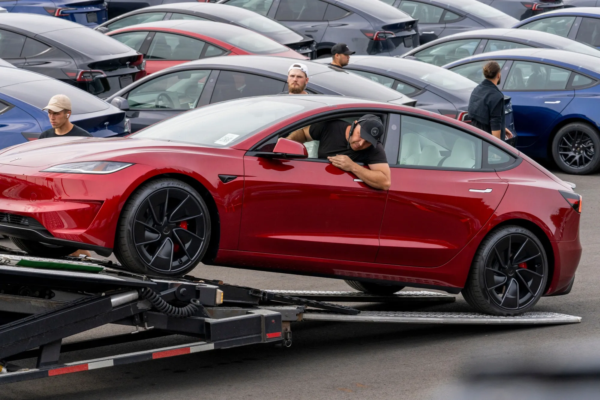 A worker unloads a Tesla Model 3&nbsp;at a logistics drop zone in Seattle.
