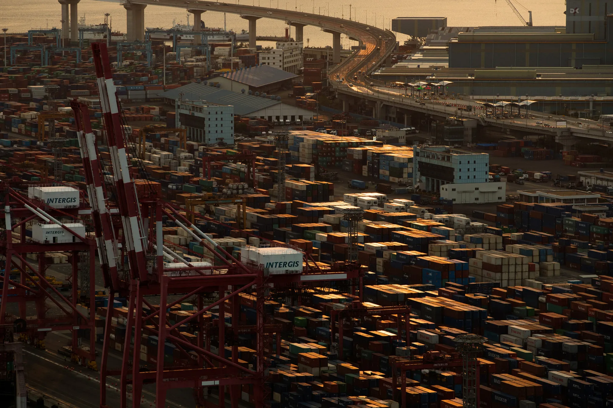 Shipping containers sit stacked among gantry cranes at a container terminal in the Port of Busan in Busan, South Korea, on July 16, 2017.
