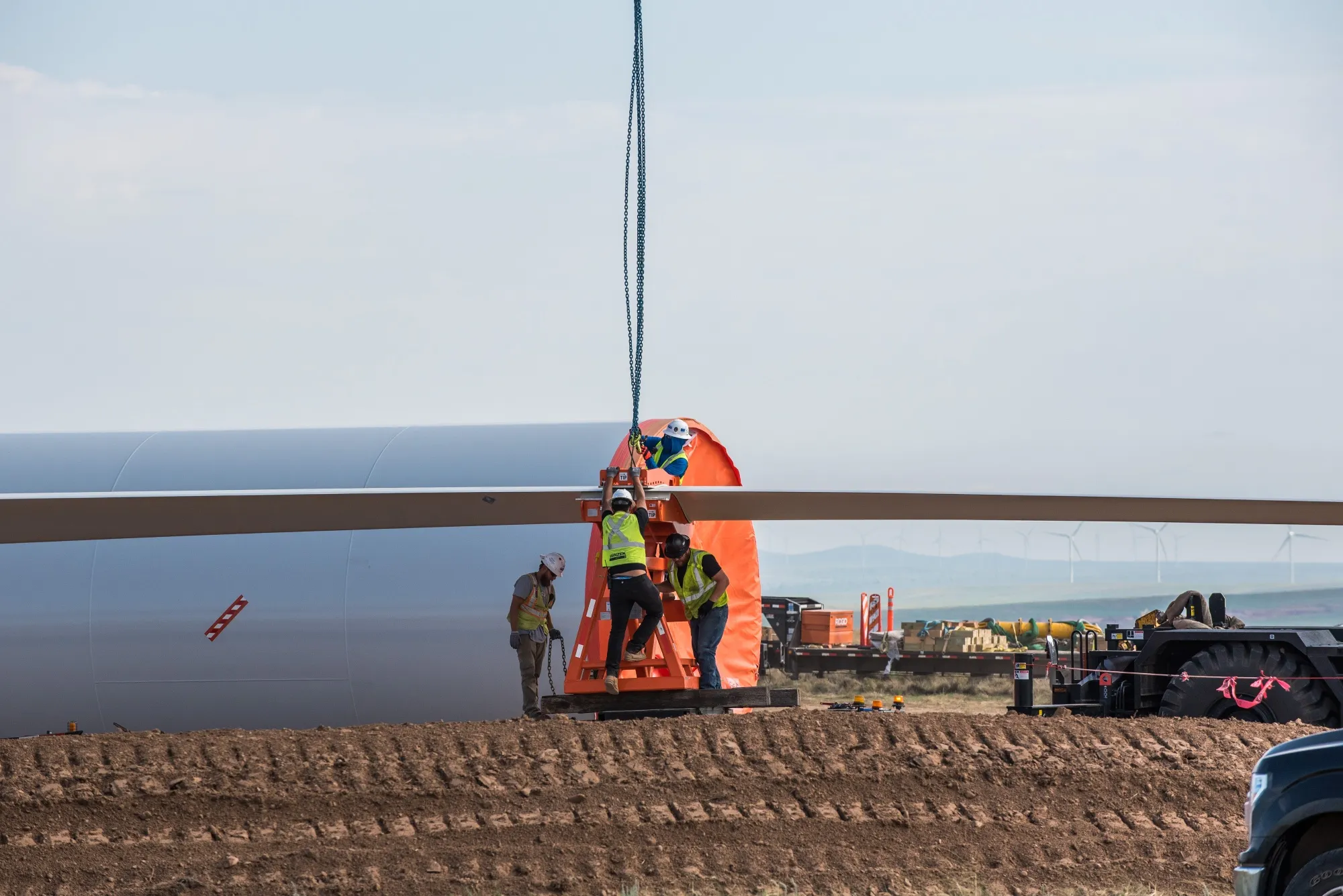 Construction workers unload a turbine blade at a wind farm in Encino, New Mexico.