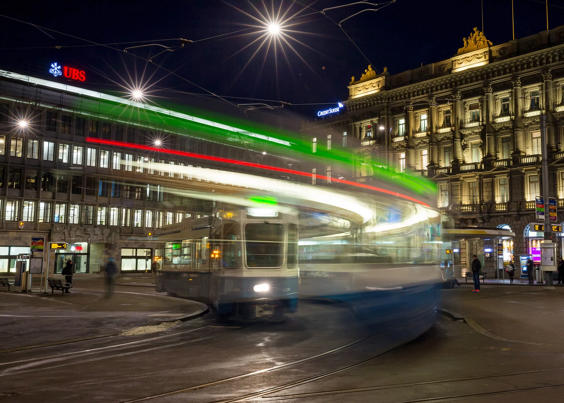 Pedestrians and a tram pass UBS Group AG, left, and Credit Suisse Group AG's headquarters on Paradeplatz in Zurich.
