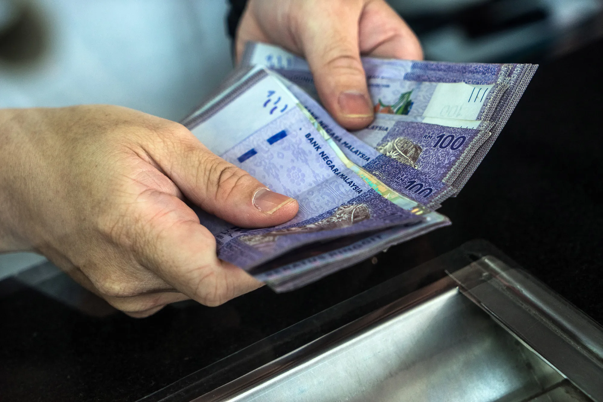 An employee counts Malaysian one-hundred ringgit banknotes at a currency exchange store in Bukit Bintang in Kuala Lumpur, Malaysia, on Aug. 25, 2015.
