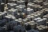 A worker stands among bundles of aluminum ingots sitting stacked at a stockyard in Wuxi, China.