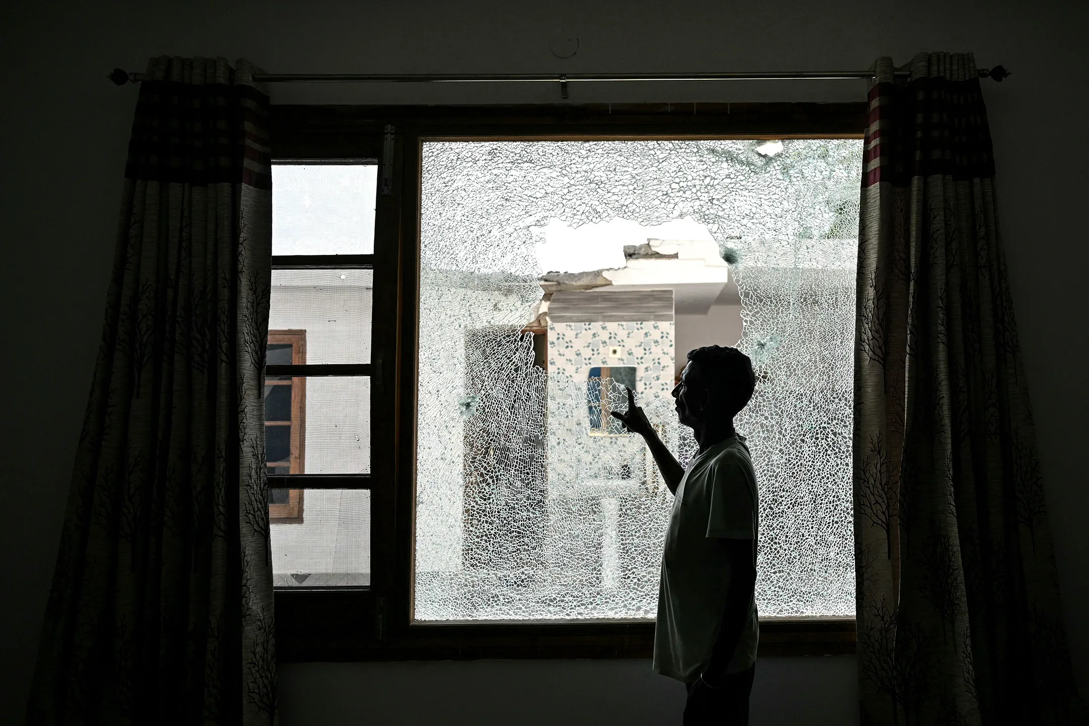 A resident shows the shattered window of a house after cross-border shelling in Arnia, India’s Jammu region, on May 10.