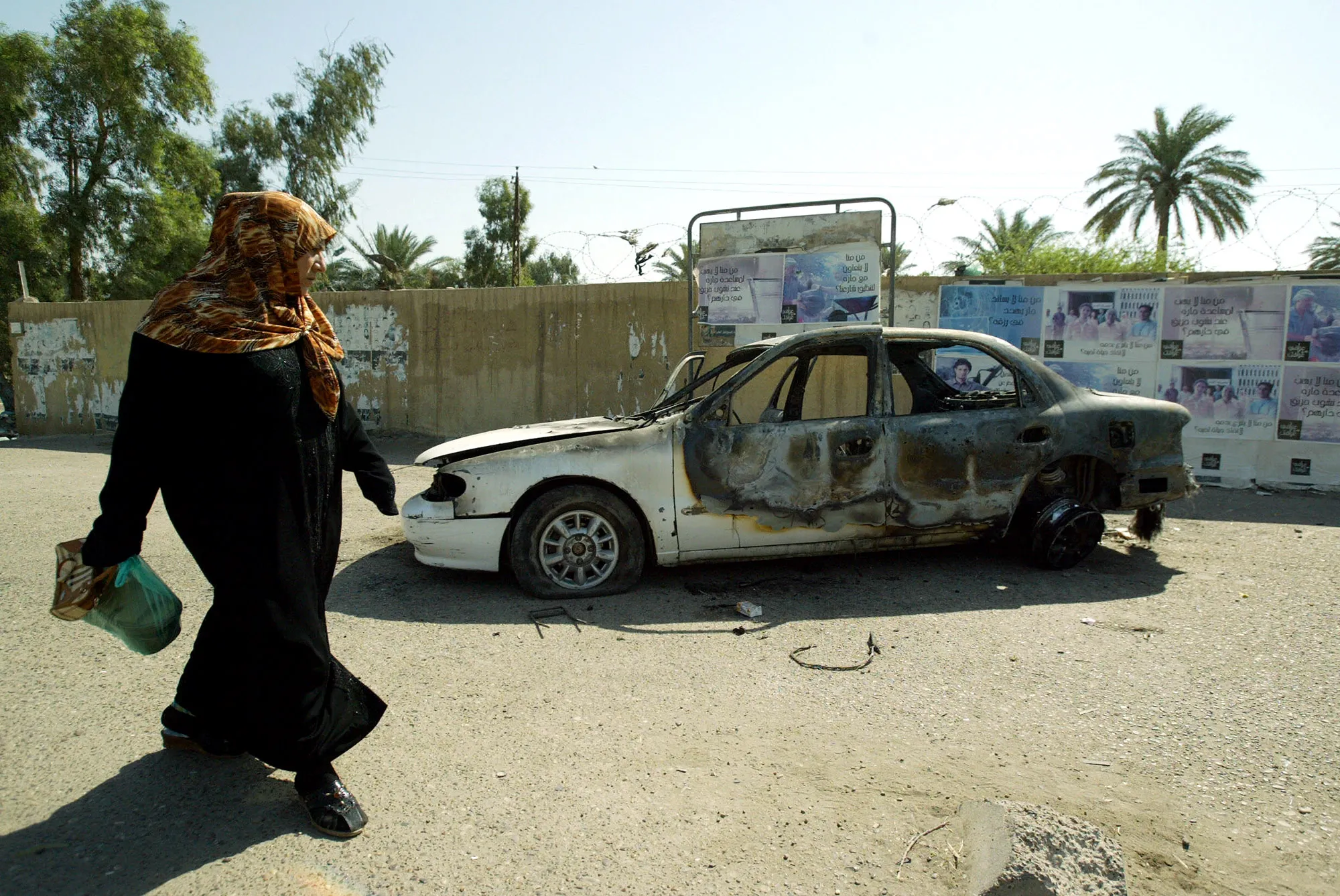 An Iraqi woman walks past&nbsp;at a burnt car on the site where Blackwater guards opened fire in the western Baghdad neighbourhood of Yarmukh in Sept. 2007.