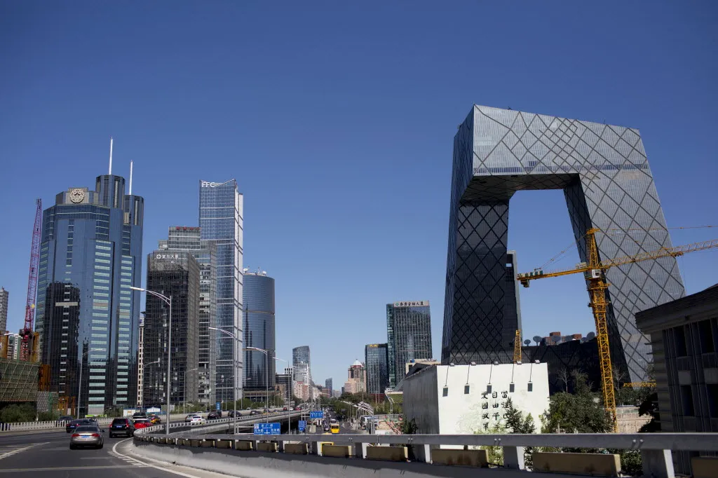 Traffic passes the China Central Television (CCTV) headquarters, right, and other commercial buildings in the central business district in Beijing, China.
