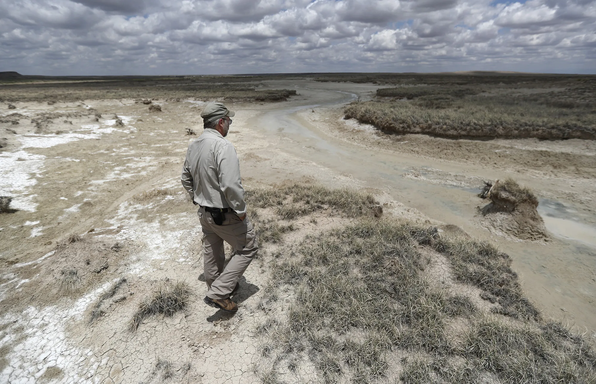 A biologist looks over a nearly dry spring at the Muleshoe National Wildlife Refuge outside Muleshoe, Texas, in May 2021.