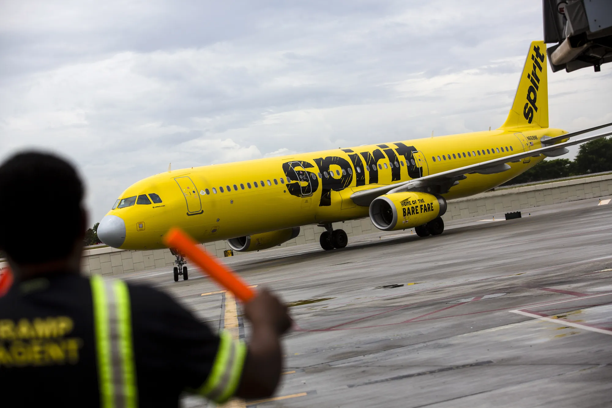 An aircraft marshal guides a Spirit Airlines Inc. plane on the tarmac at Fort Lauderdale International Airport.