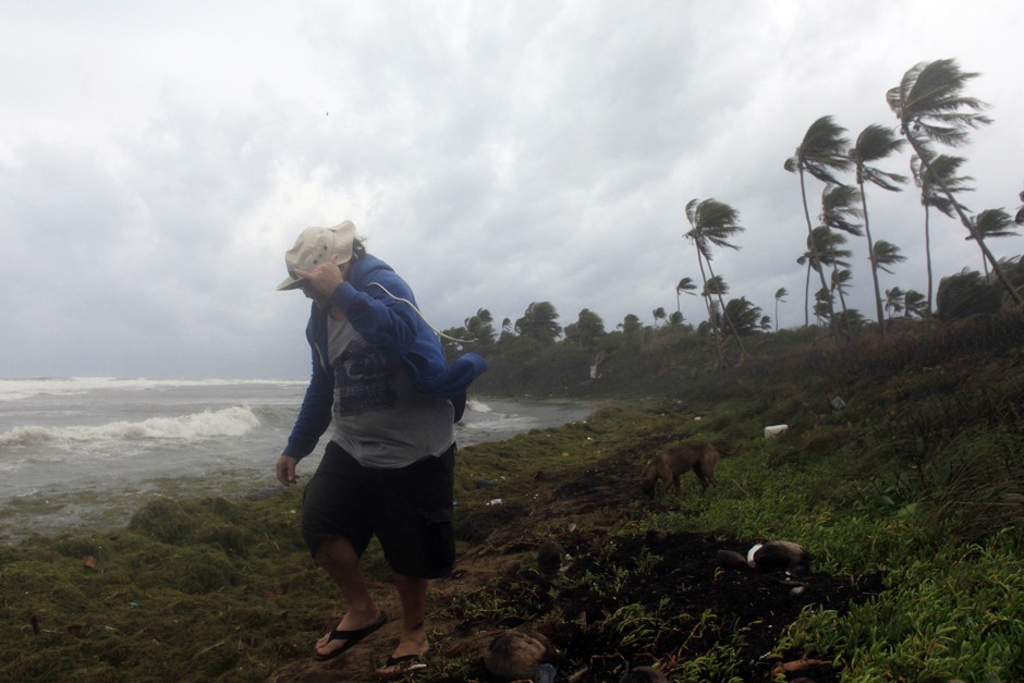 A man walks on the shore against strong winds backdropped by a rough sea as Tropical Storm Erika moves away from the area in Guayama, Puerto Rico, on August 28, 2015.