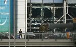 A soldier stands near broken windows after explosions at Zaventem airport near Brussels, Belgium, March 22, 2016. 