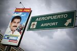 A road sign, next to a campaign poster of President Nicolás Maduro, indicates the way to Simón Bolívar International Airport, outside Caracas.