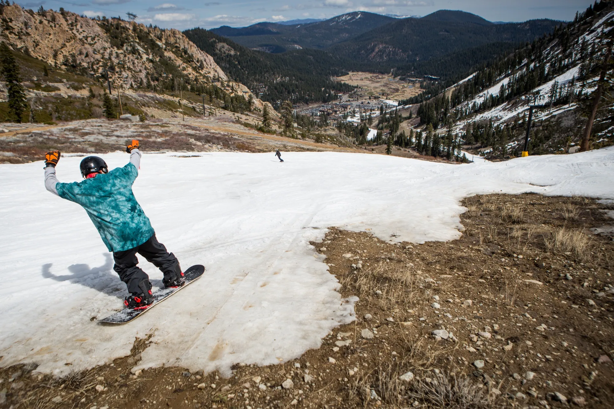 A snowboarder threads through patches of dirt in Olympic Valley, California.