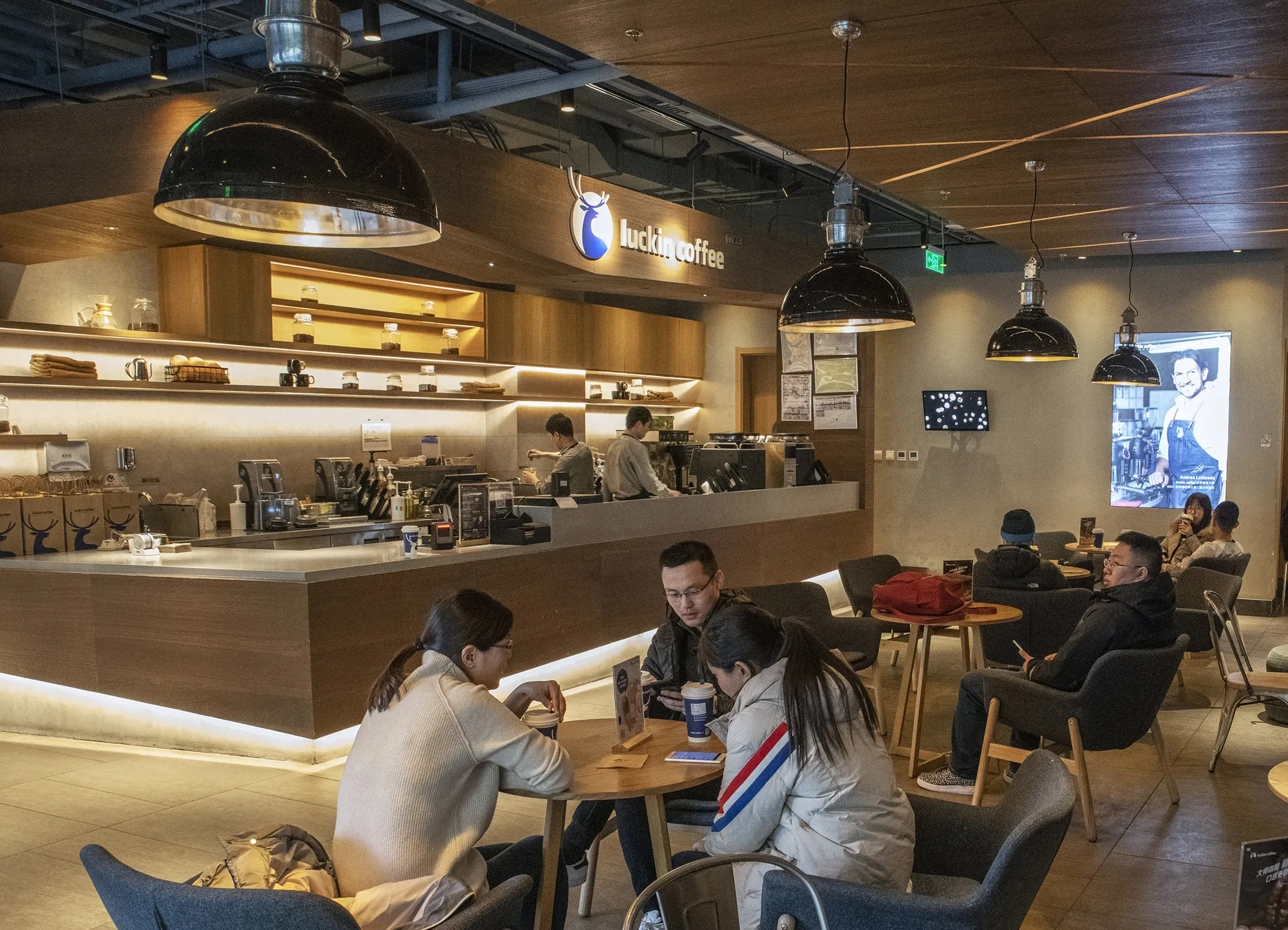 Customers sit at tables at a Luckin Coffee shop&nbsp;in Beijing.