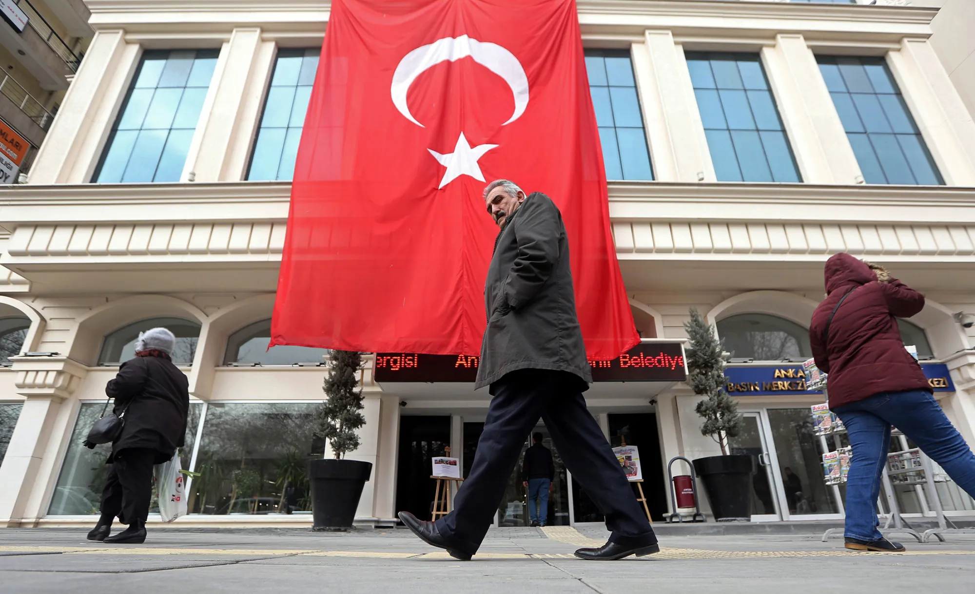Pedestrians pass a giant Turkish national flag hanging from a building in Ankara, Turkey, on Dec. 20, 2016.
