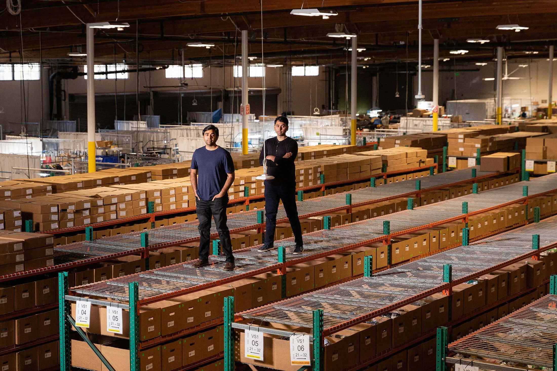 Anil and Sunil Varanasi next to one of their Meter access points hanging from the ceiling at a warehouse in Brisbane, Calif.