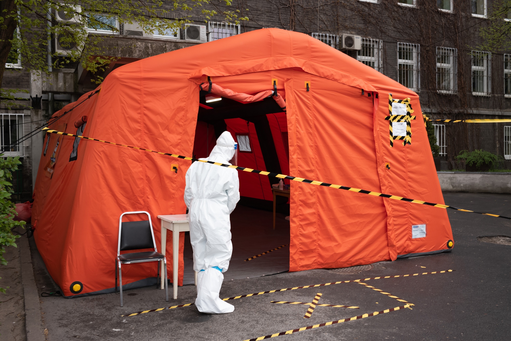 A medical worker wearing personal protective equipment beside a tent set up for visitor temperature checks outside a hospital in Warsaw.