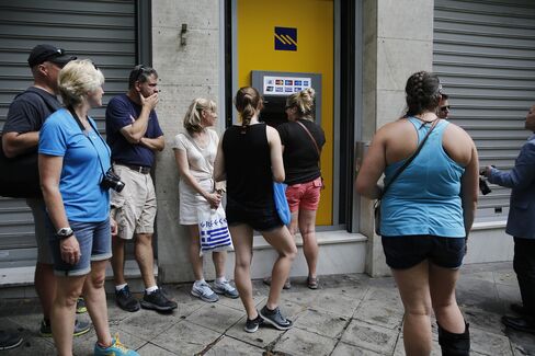 People wait in line at an ATM at a Piraeus Bank branch in Athens