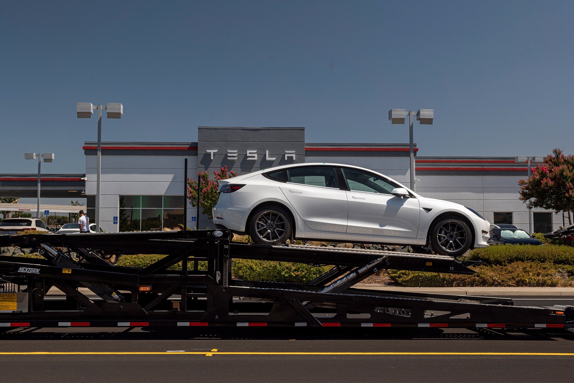 A Tesla Model 3 vehicle on an auto carrier in front of a store in Rocklin, California.