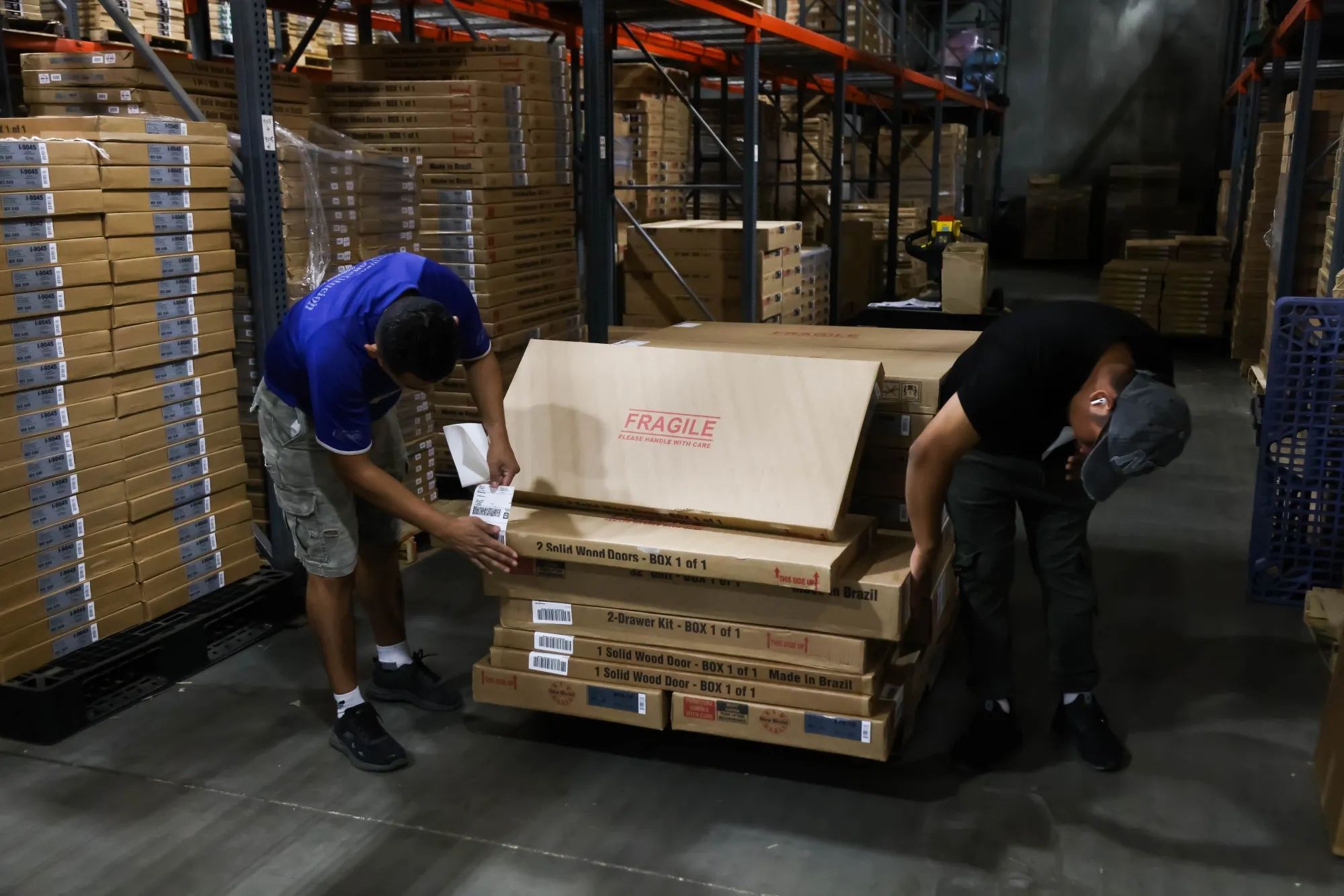 Workers apply shipping labels to boxes of furniture for shipment at a warehouse in Linden, New Jersey.