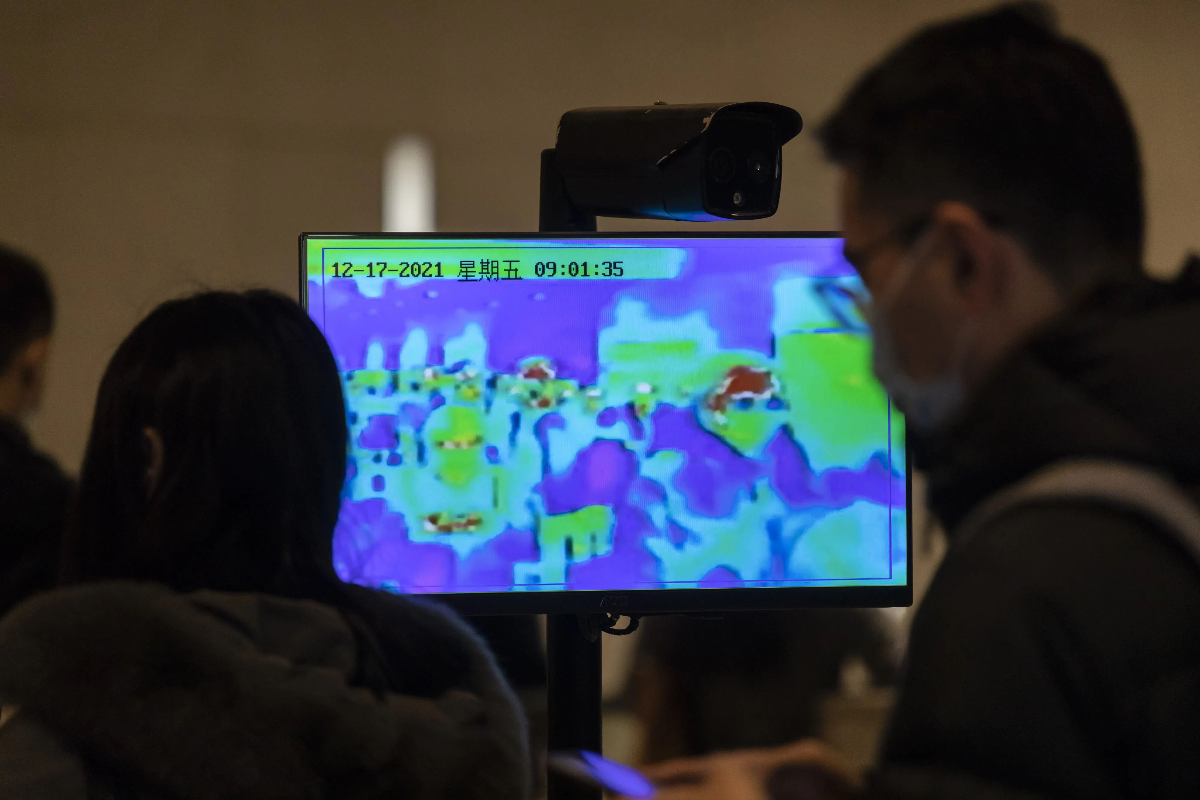 A monitor displays a thermographic image of commuters at a subway station in Shanghai in December 2021.