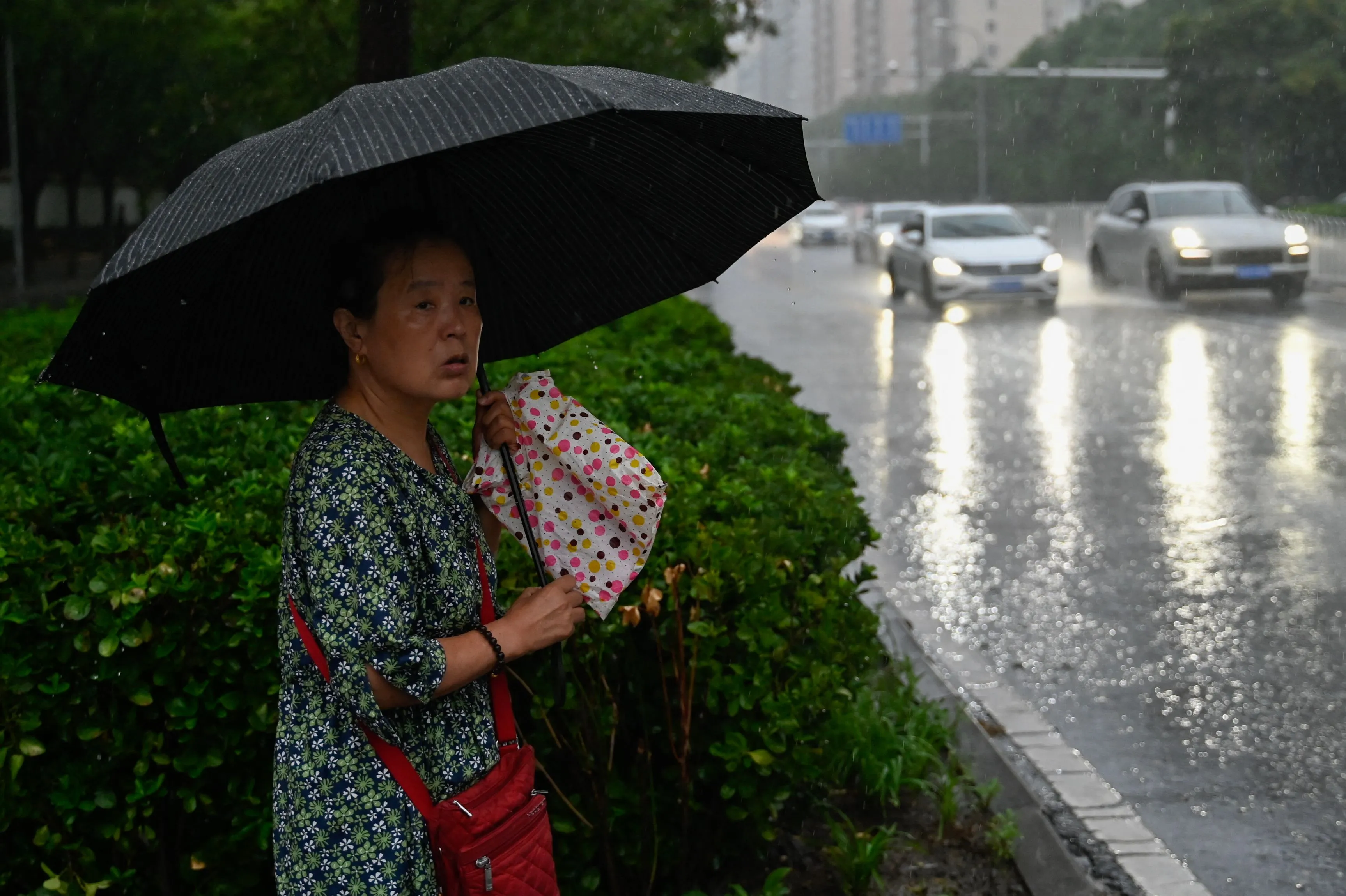 A woman shelters from the rain with an umbrella in Beijing on July 31.