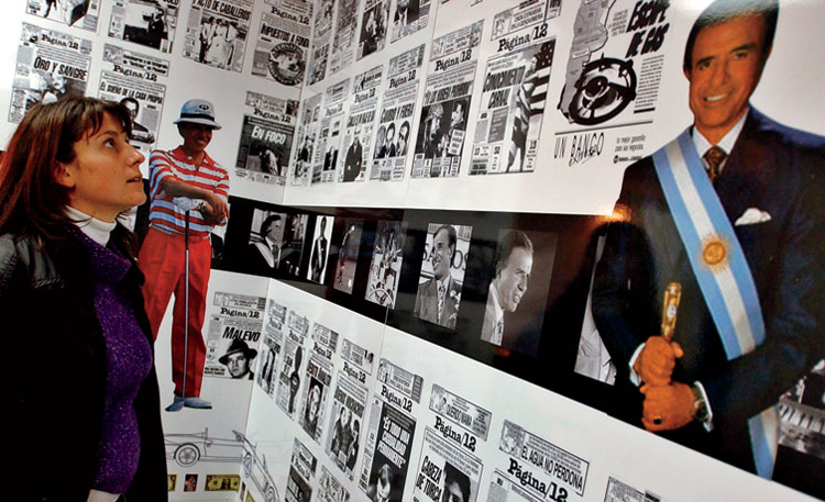A visitor at the Museum of Foreign Debt in Buenos Aires. To the right is an image of former president Carlos Menem, whose efforts to control inflation produced a heavy debt load for the country.