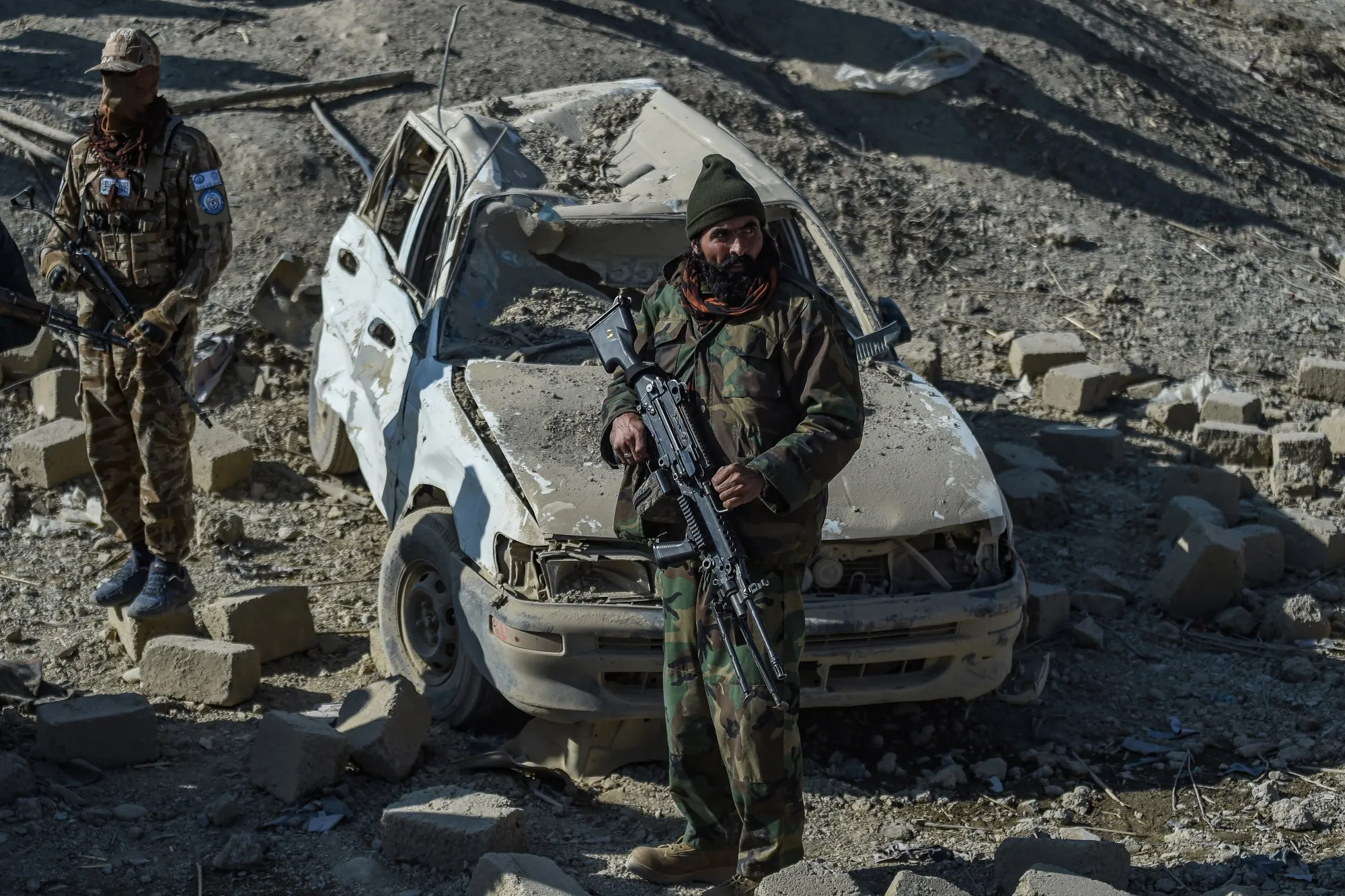 Taliban security personnel stand guard near a damaged car two days after air strikes by Pakistan in Paktika province, on Dec. 26.