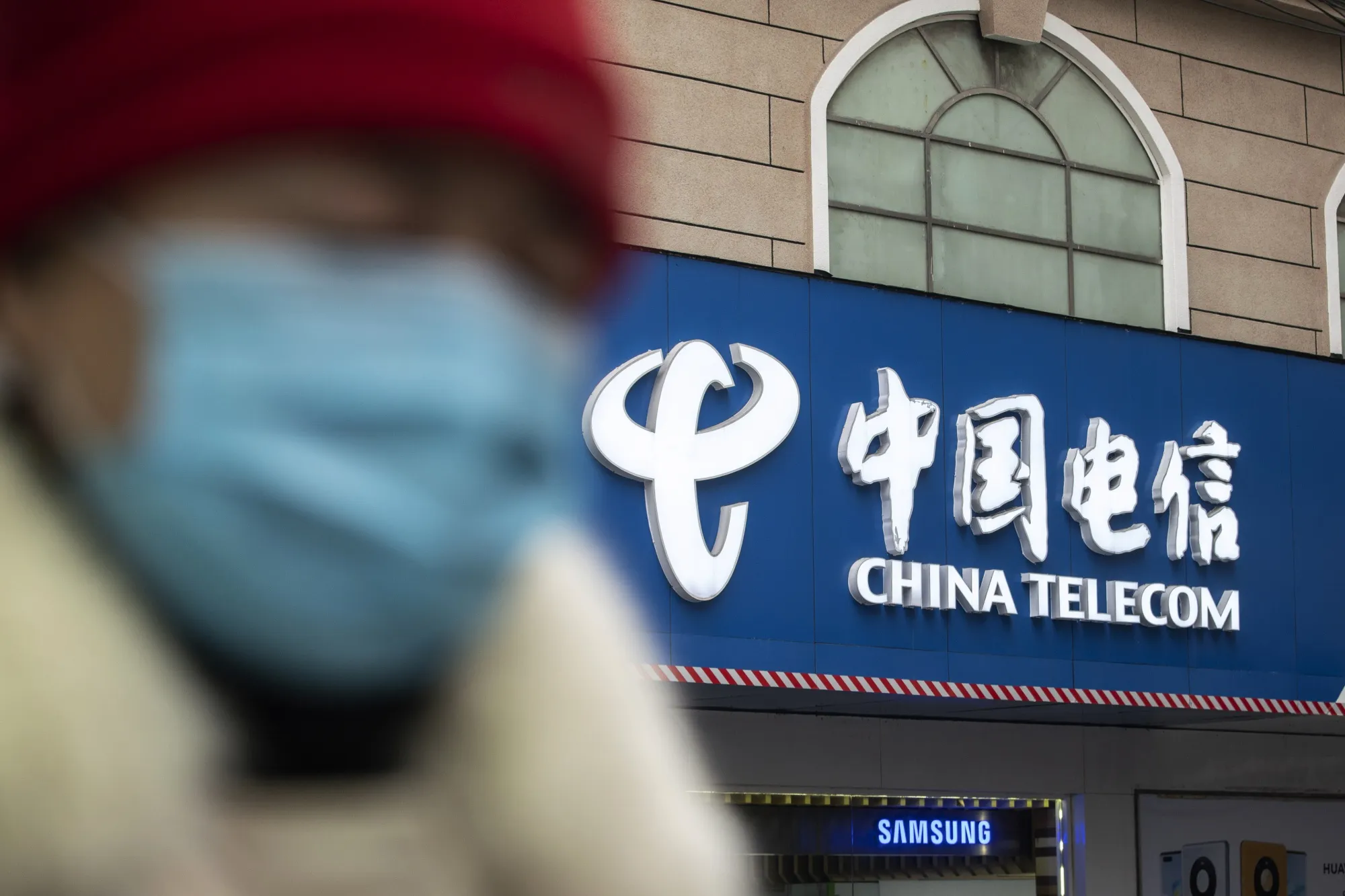 A pedestrian walks past a China Telecom Corp. store in Shanghai.