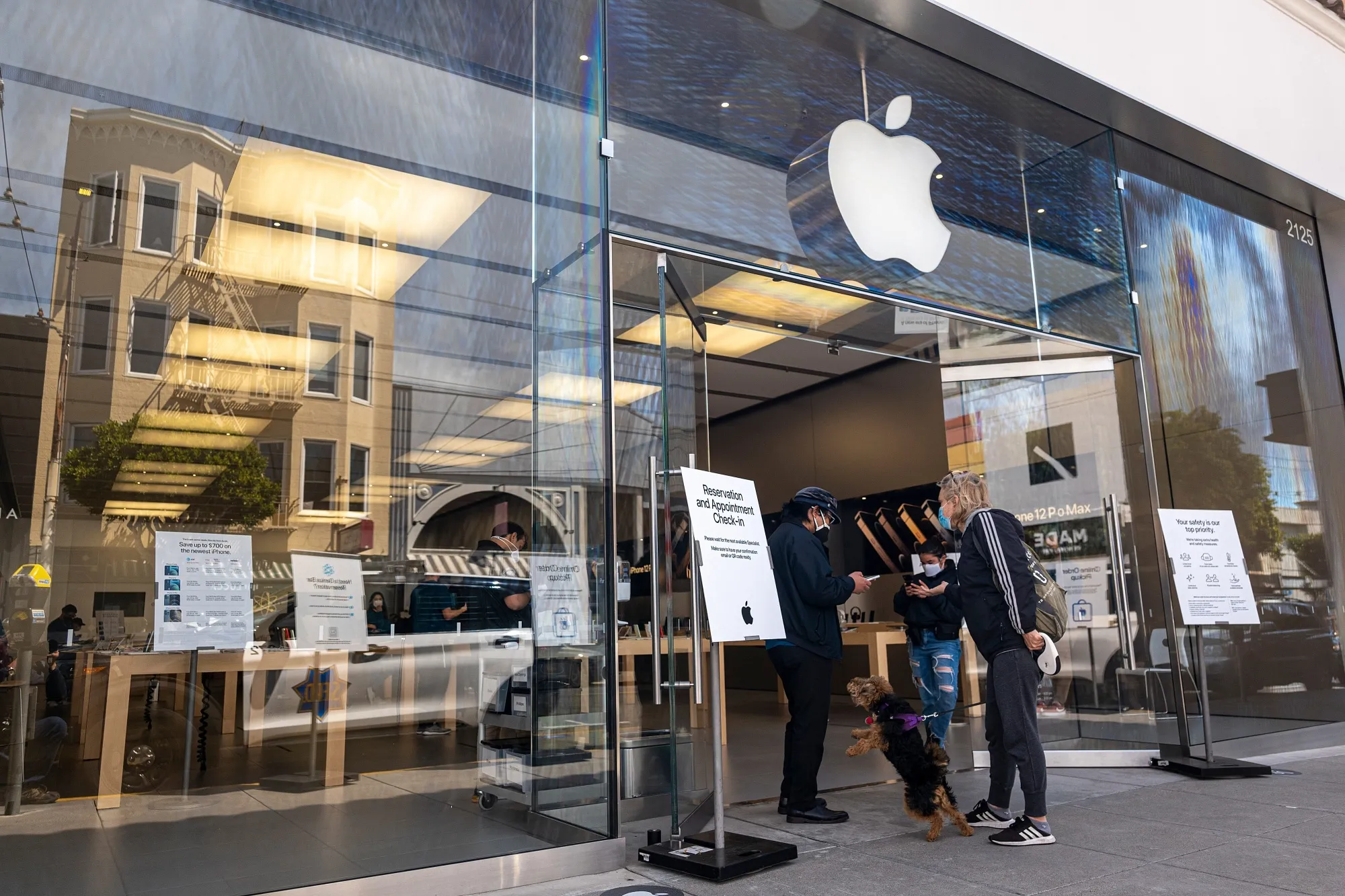 A customer wearing a protective mask waits to enter an Apple store in San Francisco.