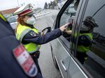 An Austrian police officer checks a driver's vaccination certificate on a smartphone during a traffic control in Graz, Austria, on November 15, 2021,