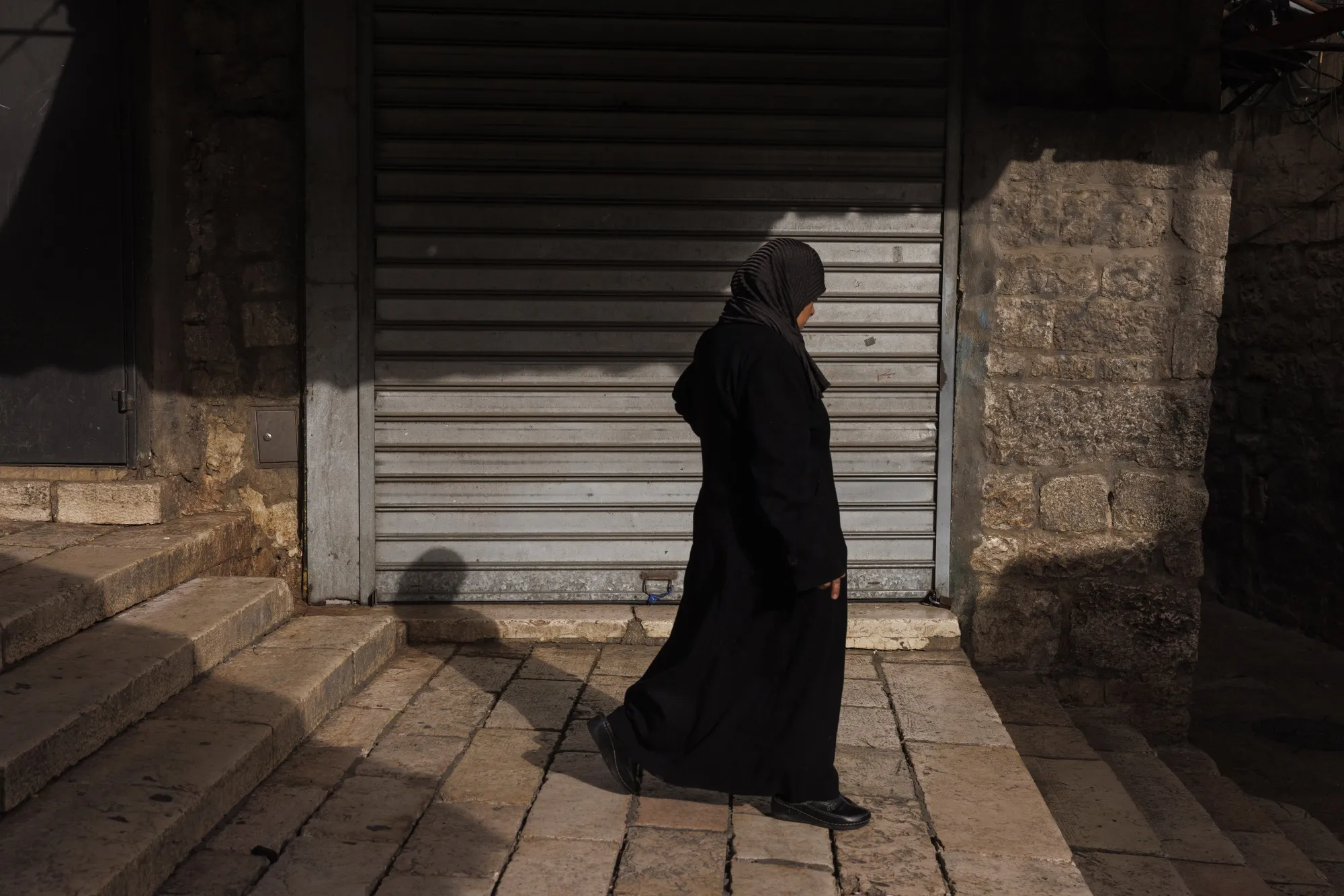 A pedestrian passes a shuttered store in the Old City of Jerusalem, West Bank.
