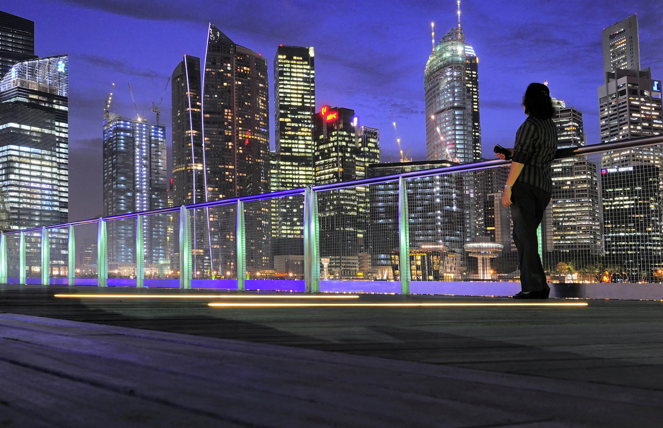 A woman on the waterfront boardwalk of the Marina Bay Sands shopping mall takes in the view of the central business district skyline, in Singapore, on Wednesday, Oct. 13, 2010. Singapore's economy contracted last quarter as manufacturing eased, and the central bank said it will widen the range its currency can trade in to absorb greater volatility in global financial markets.
