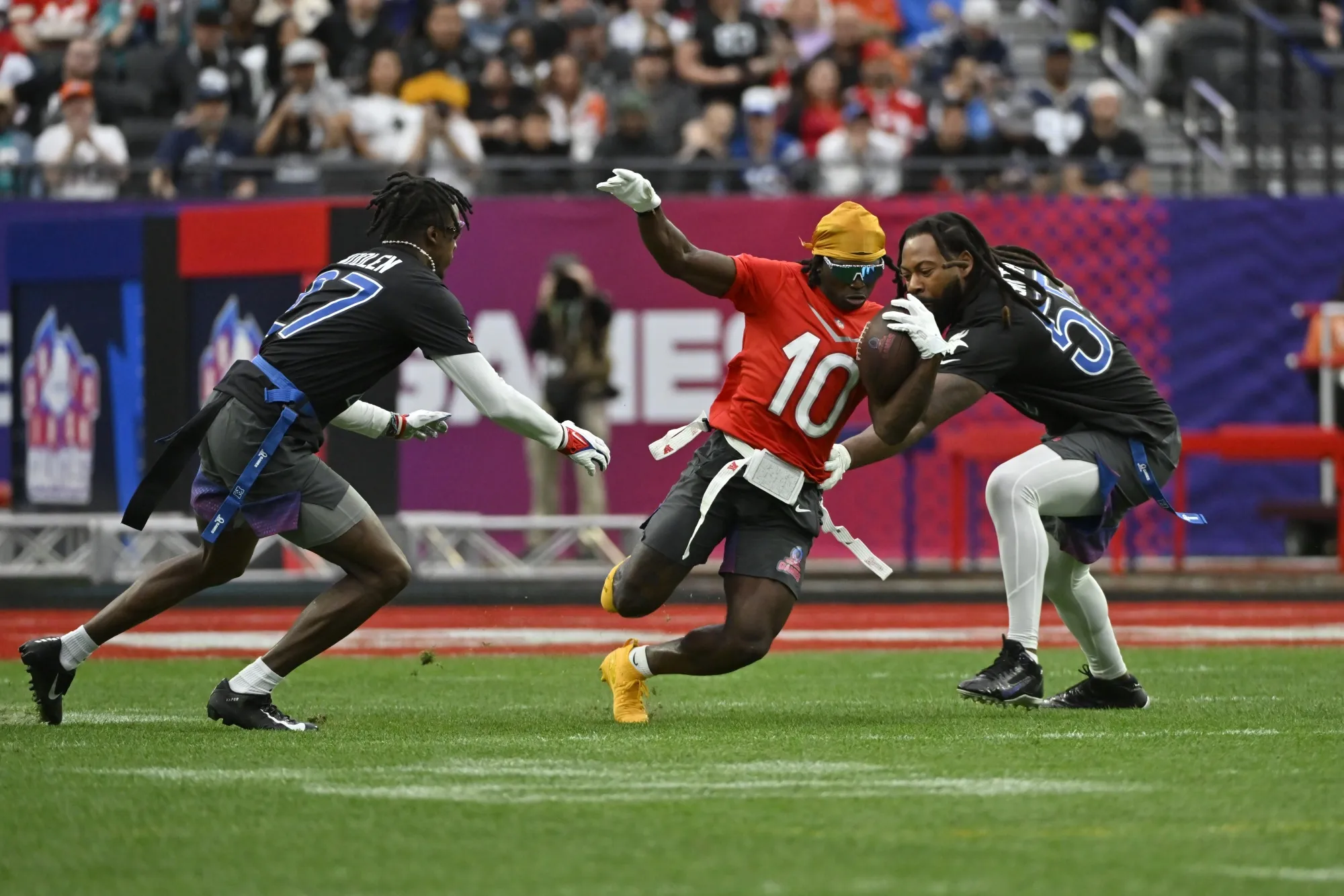AFC wide receiver Tyreek Hill (10) of the Miami Dolphins carries the ball against NFC cornerback Tariq Woolen (27) of the Seattle Seahawks and outside linebacker Za'Darius Smith (55) of the Minnesota Vikings during the flag football event at the NFL Pro Bowl, Feb. 5, 2023, in Las Vegas. Flag football took a key step toward becoming an Olympic sport in 2028, a victory for the NFL and organizers in Los Angeles who will bring a distinctly American sport to the Summer Games as they return to the United States for the first time in 32 years. (AP Photo/David Becker, File)
