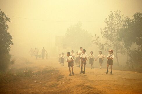 Indonesian schoolchildren walk on a path shrouded in haze from a massive fire in 1997.