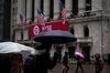 Pedestrians carrying umbrellas walk past the New York Stock Exchange (NYSE) in New York, U.S., on Friday, April 6, 2018. U.S. stocks fell and Treasuries rose as investors assessed the latest threat to the global trade order and a disappointing jobs report.