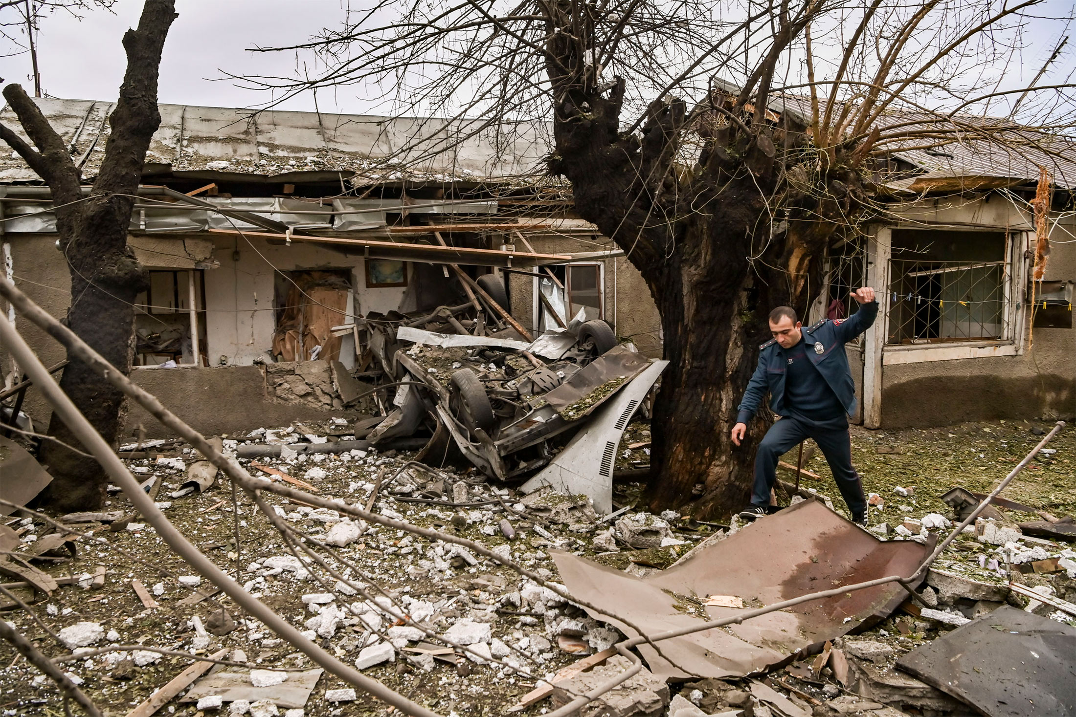 A police officer steps over debris in the yard of a destroyed house after shelling in the Nagorno-Karabakh region's main city of Stepanakert on Oct. 7.