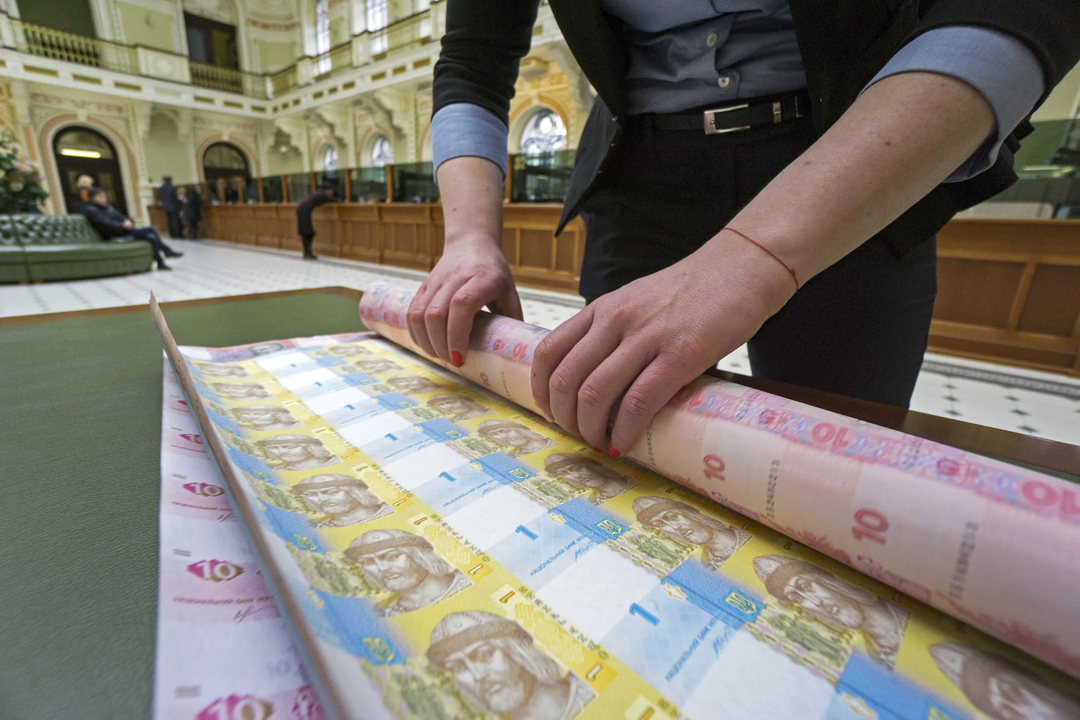 A bank worker rolls up uncut sheets of ten and one hryvnia banknotes at the headquarters of the National Bank of Ukraine in Kiev, Ukraine.
