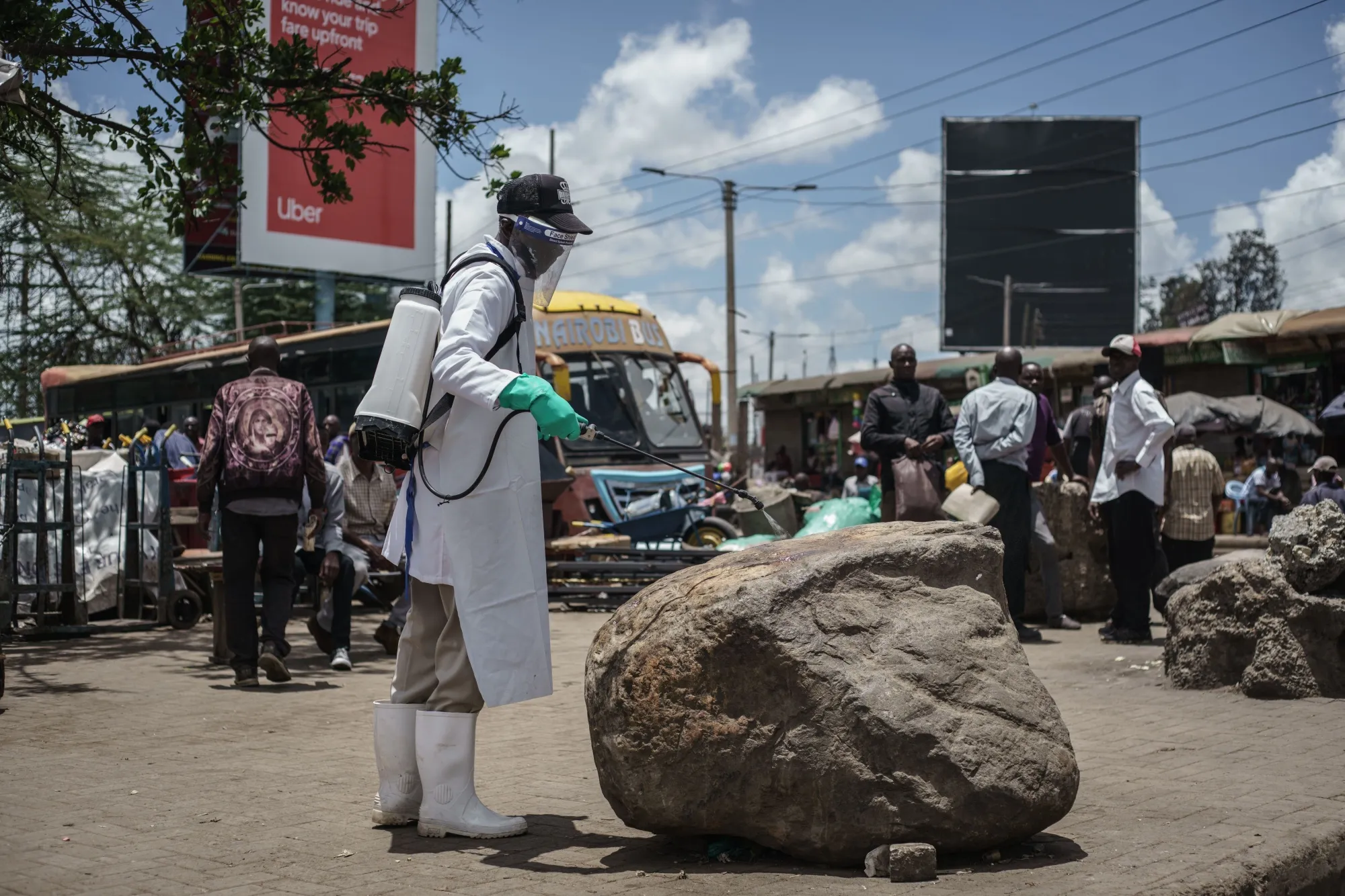 A staff member of Kenya's Ministry of Health sprays disinfectant on a rock which people sit on to curb the spread of the COVID-19 coronavirus at the Gikomba Market in Nairobi.