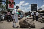 A staff member of Kenya's Ministry of Health sprays disinfectant on a rock which people sit on to curb the spread of the COVID-19 coronavirus at the Gikomba Market in Nairobi.