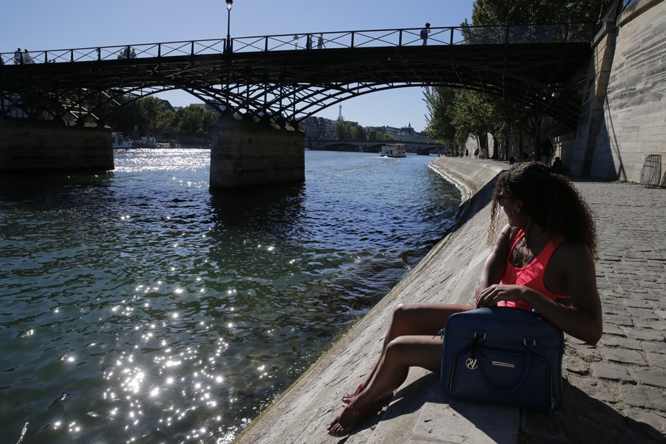 A woman relaxing on the banks of the Seine in summer 2016. The wall behind her contains a major road tunnel, closed to traffic last autumn.